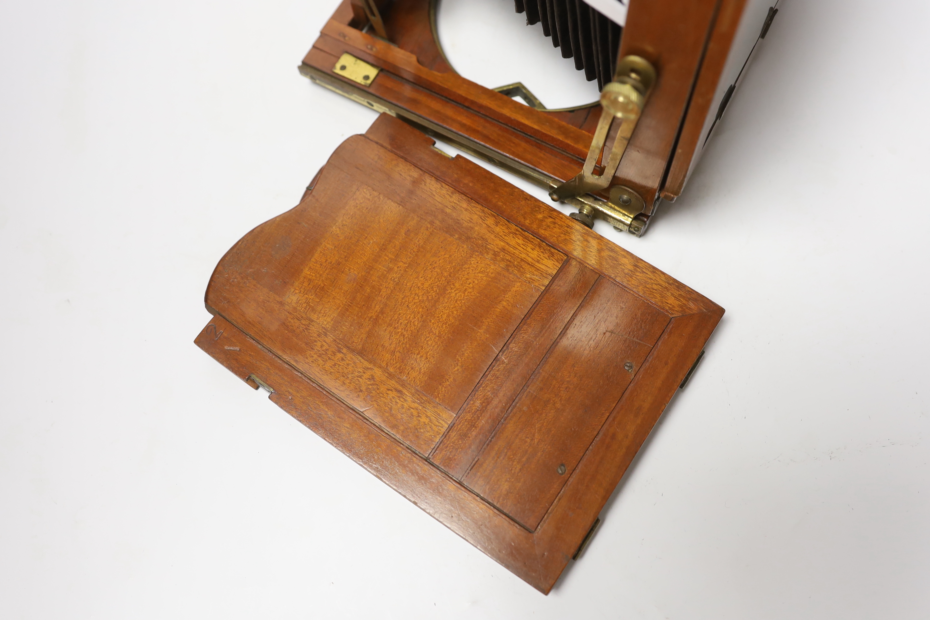 A late nineteenth century brass and mahogany half plate bellows camera with a lens and a shutter action by Taylor, Taylor & Hobson, Leicester, together with a negative holder
